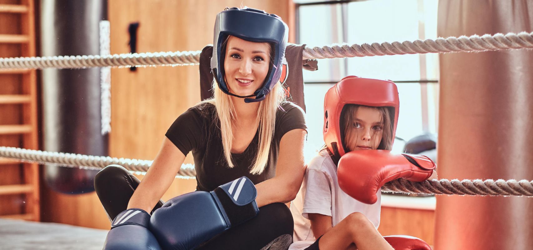 Trainerin mit Kind in Kickboxmontur im Ring sitzend